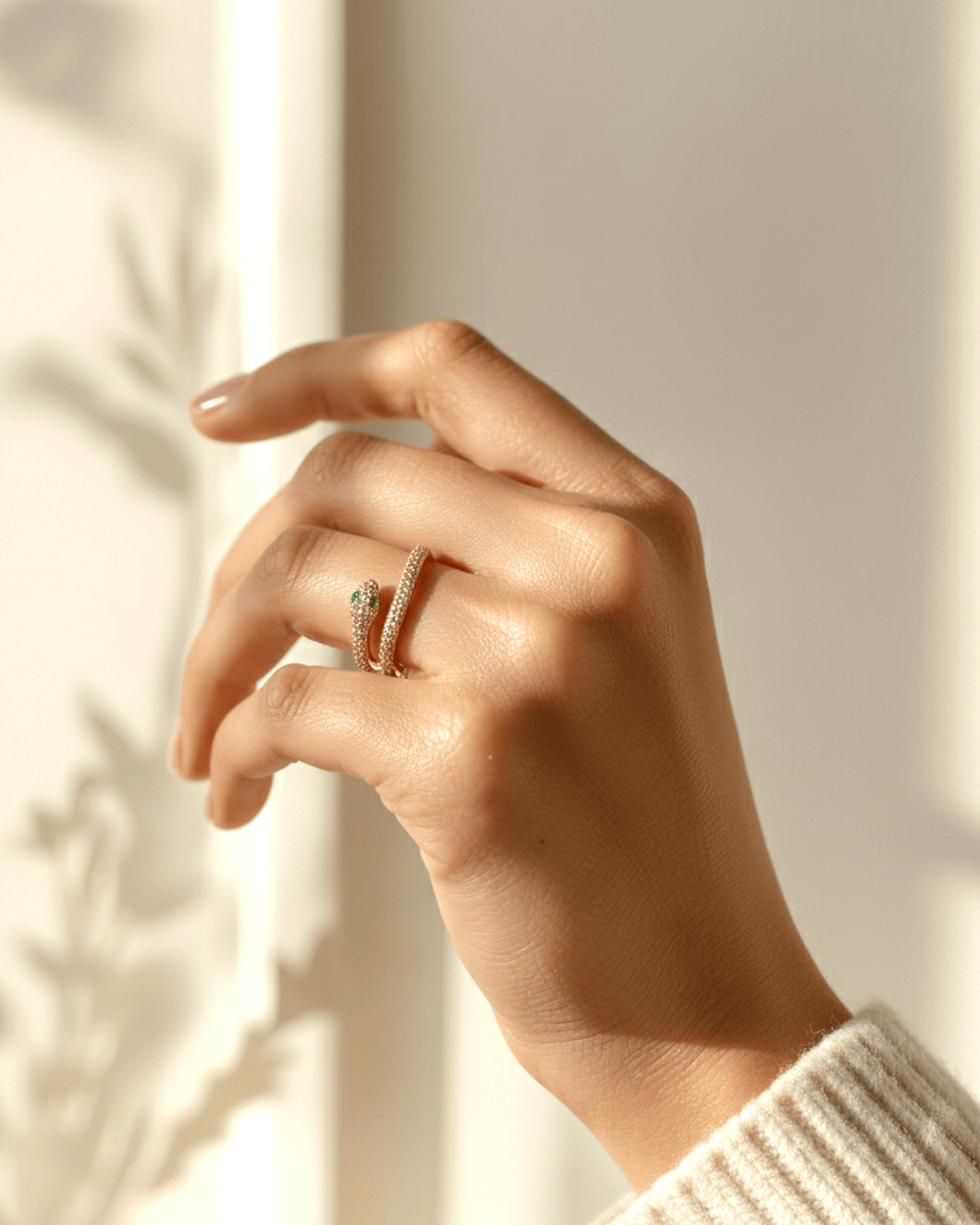 A close-up photograph features a person's hand wearing a gold-tone wrap ring shaped like a snake on their ring finger. The sn