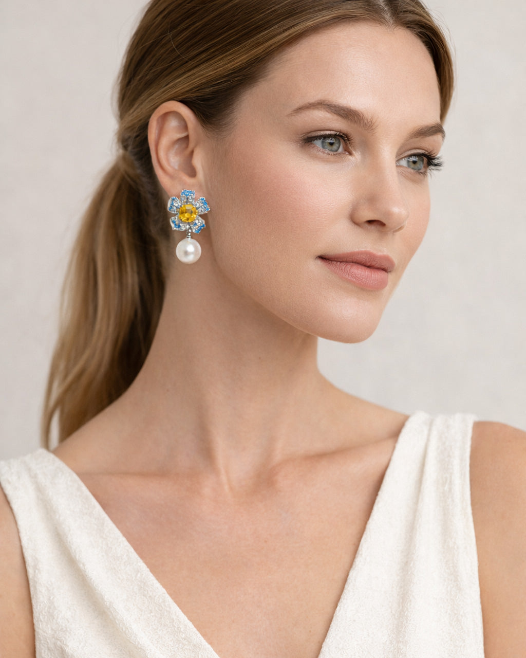 Model wearing Jadejuri blue flower pearl drop earrings, elegant close-up portrait
