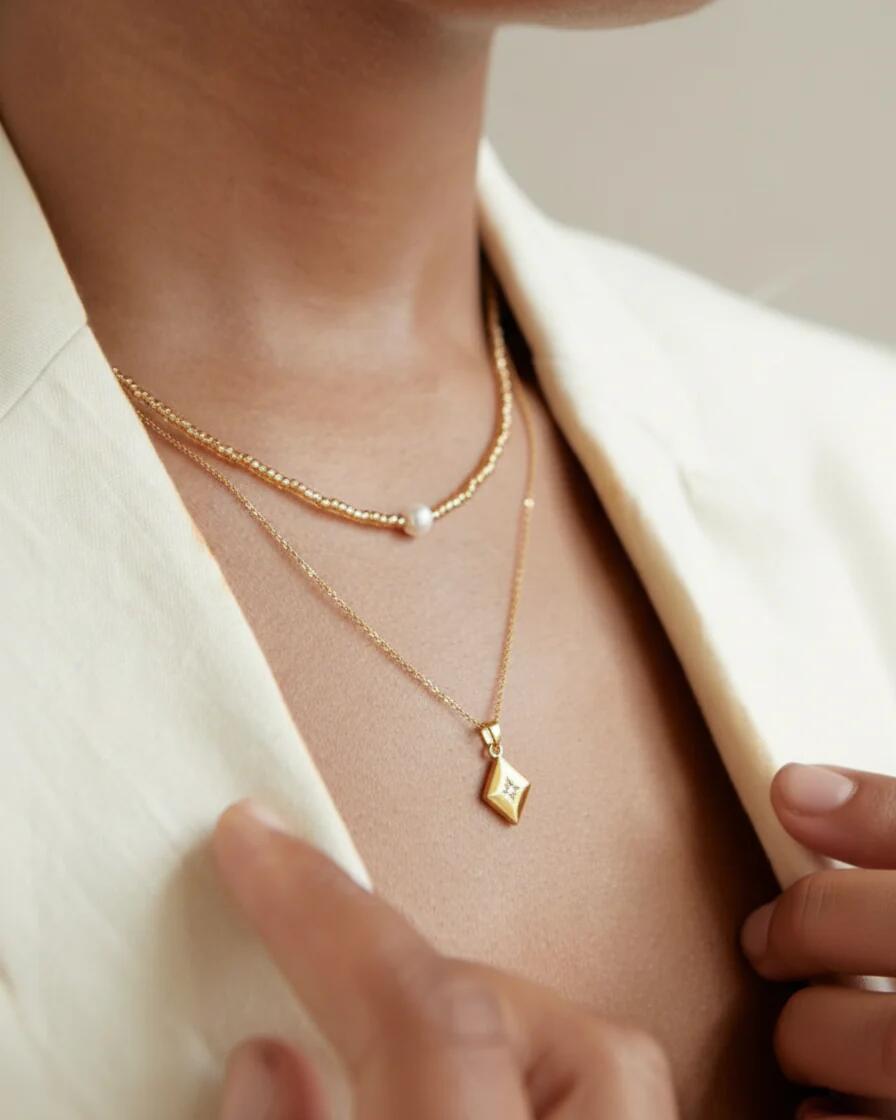 Layered 18K gold plated necklace with pearl and star pendant on model, minimalist style