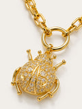 Gold beetle-shaped charm with 'AB' initials on a gold chain against a white background