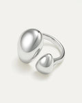 Silver ring with two rounded elements on a light gray background