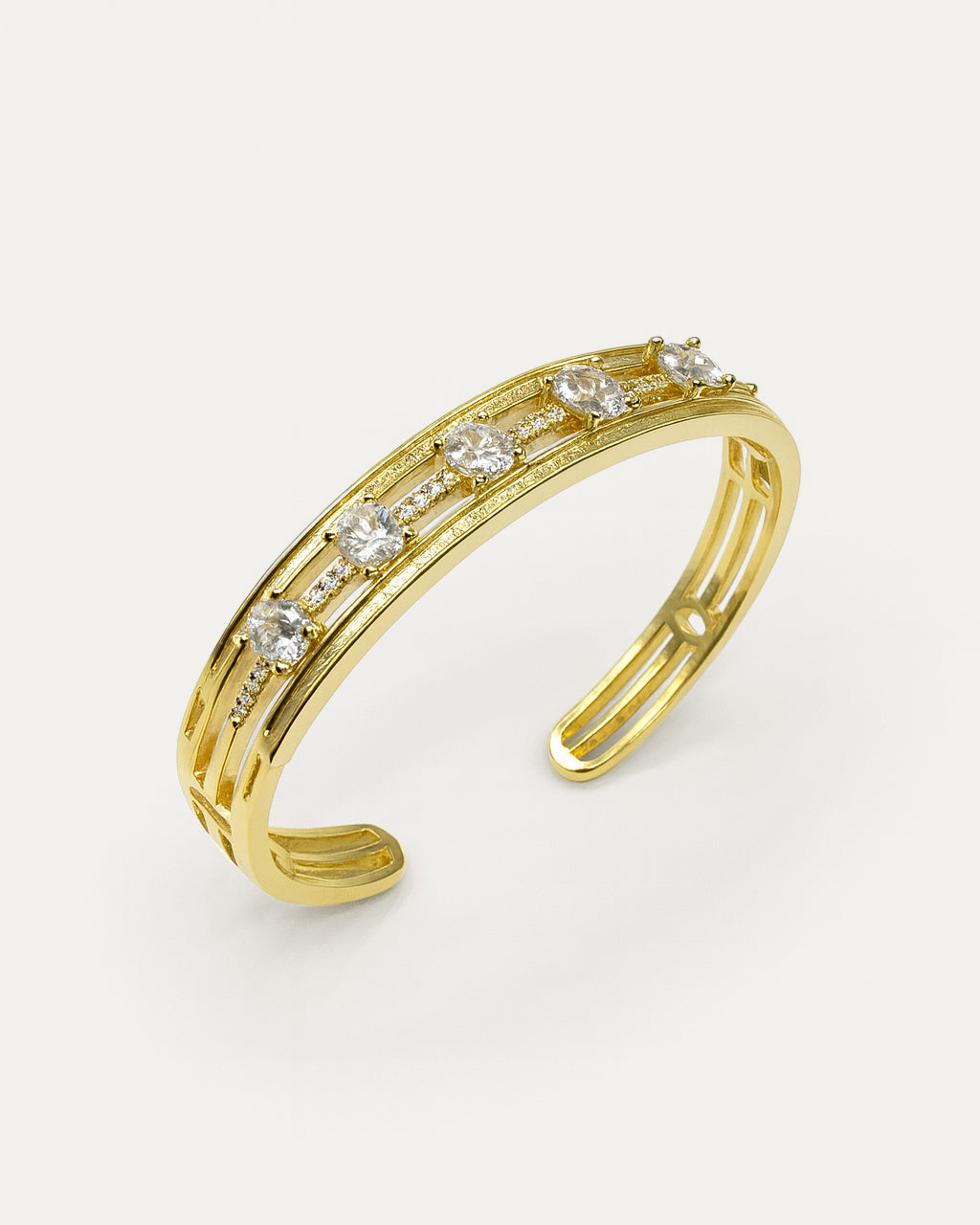 Gold bracelet with embedded diamonds on a light gray background