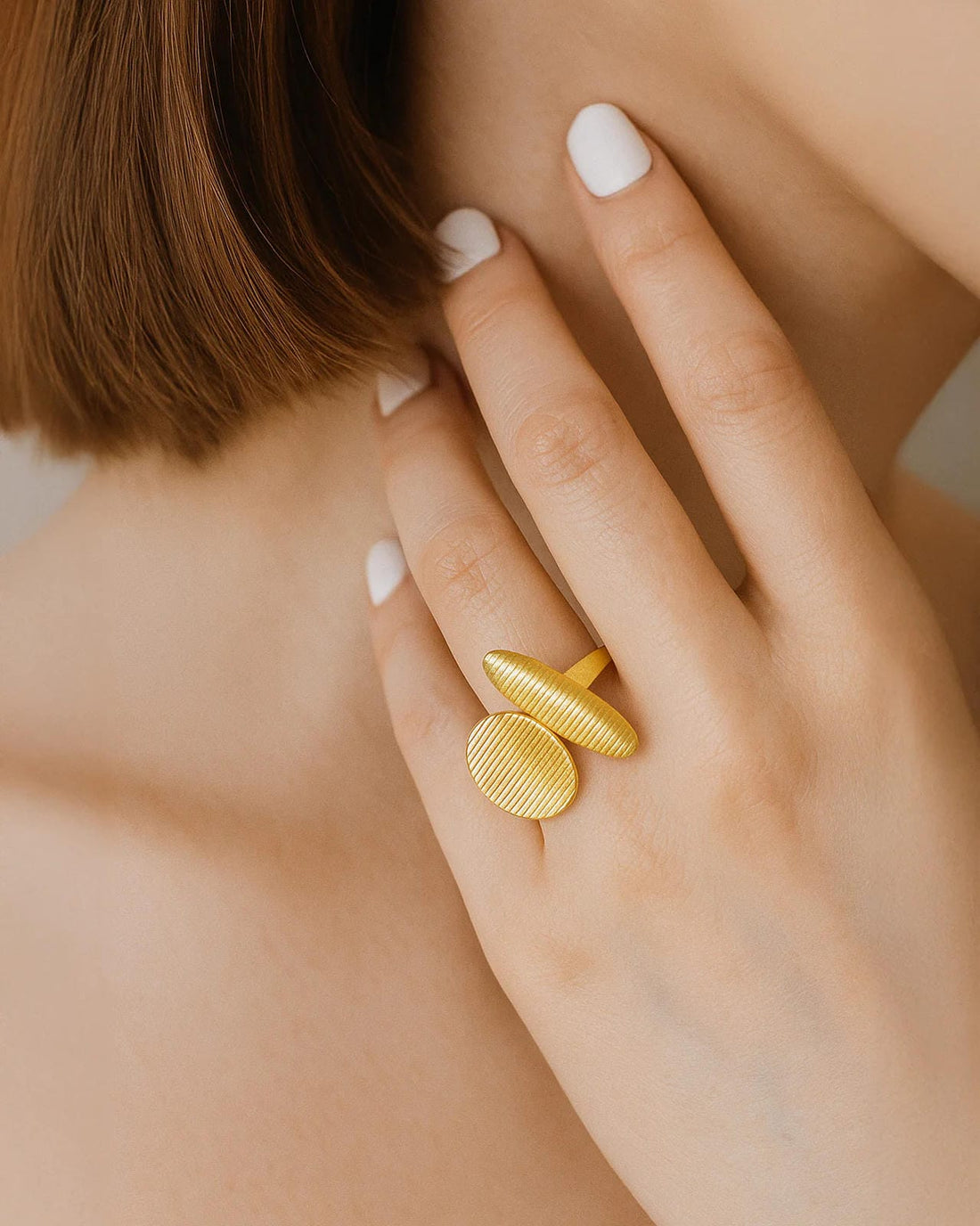 Asymmetrical gold ring with ribbed oval and capsule-shaped open ends