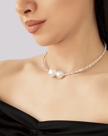 Close-up of a pearl choker necklace featuring two oversized faux pearls and a silver-tone beaded strand, worn on a woman's ne
