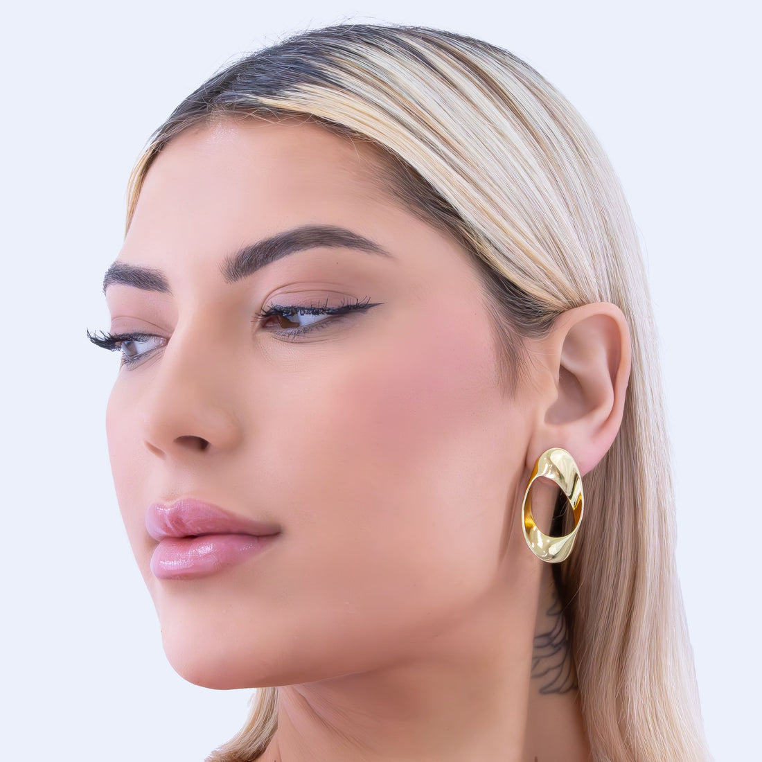 Modern asymmetric gold-plated hoop earrings with twisted oval design and hollow center, featuring a high-polish finish and contemporary sculptural shape