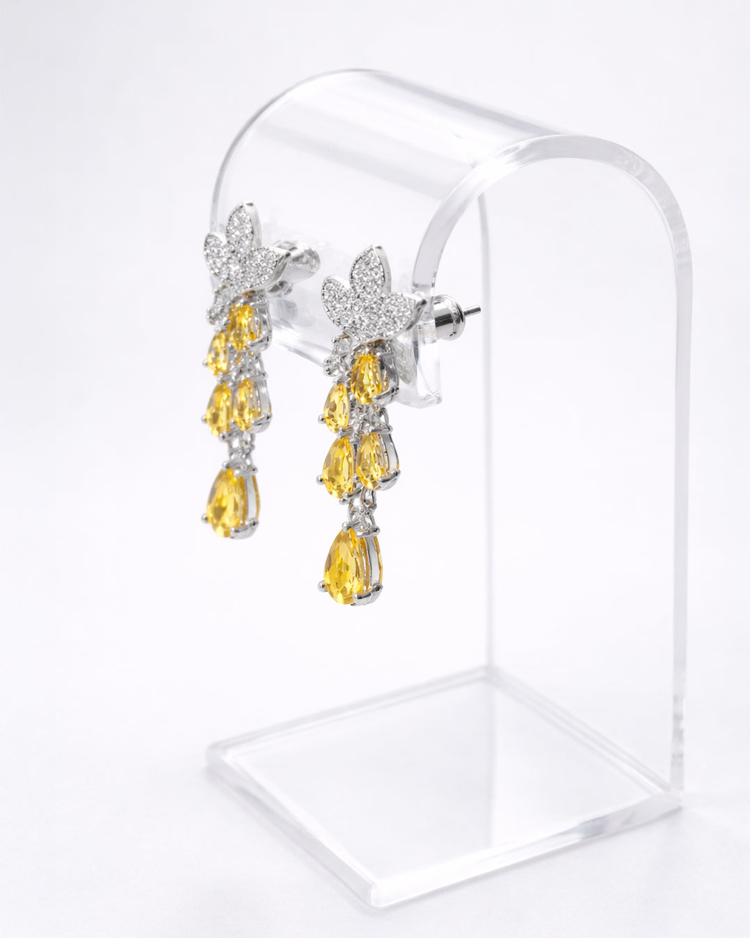 Floral cubic zirconia drop earrings with yellow stones displayed on clear stand