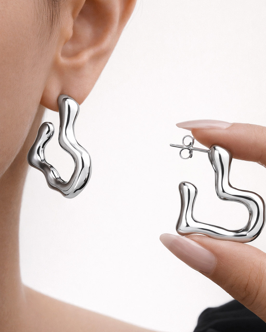 Minimalist sculptural silver stud earrings worn on ear, modern organic design
