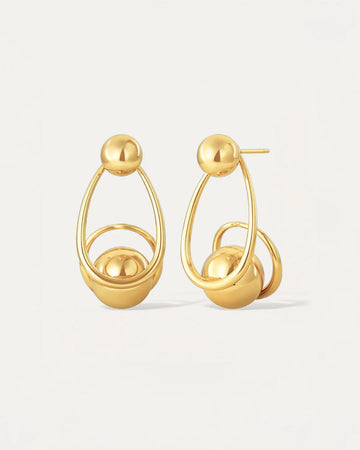 Gold sculptural drop earrings with overlapping loops and sphere accents, worn on model.
