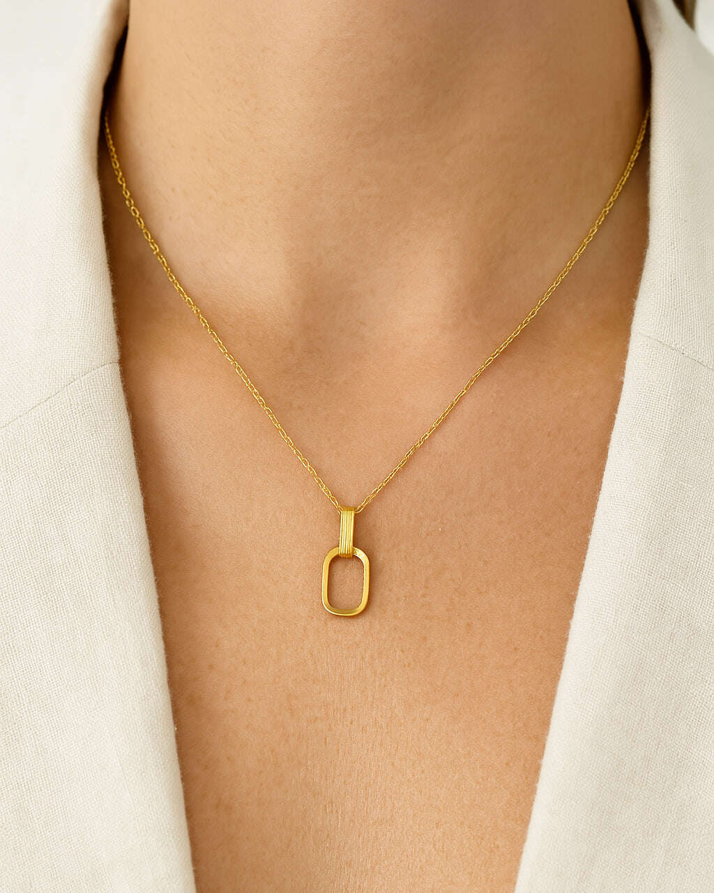Gold necklace with a unique pendant on a light gray background