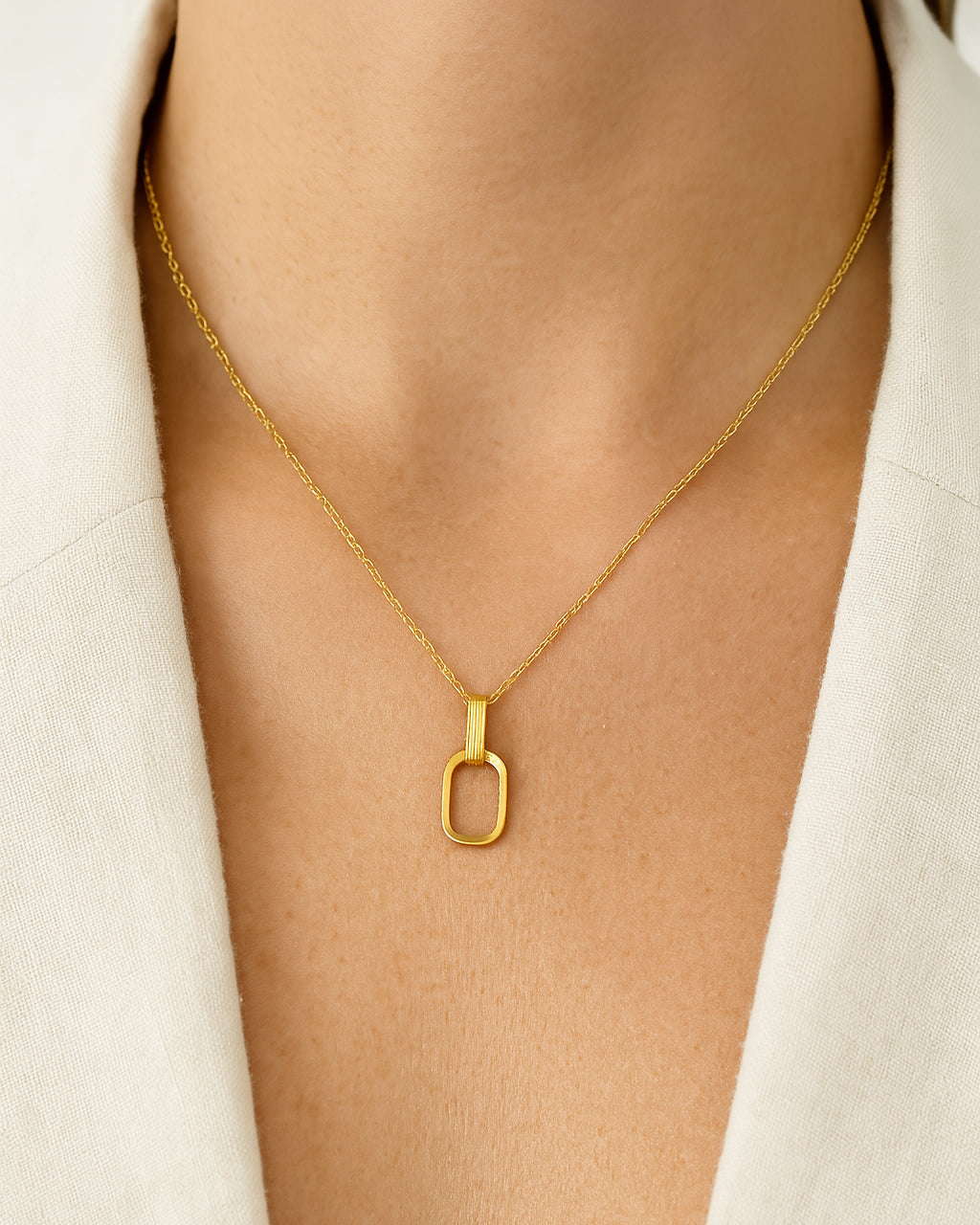 Gold necklace with a unique pendant on a light gray background
