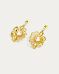 Intricate gold floral dangle earrings with a delicate chain. Perfect for adding a touch of elegance to any outfit.