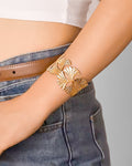 Gold bracelet on a person's wrist with a neutral background
