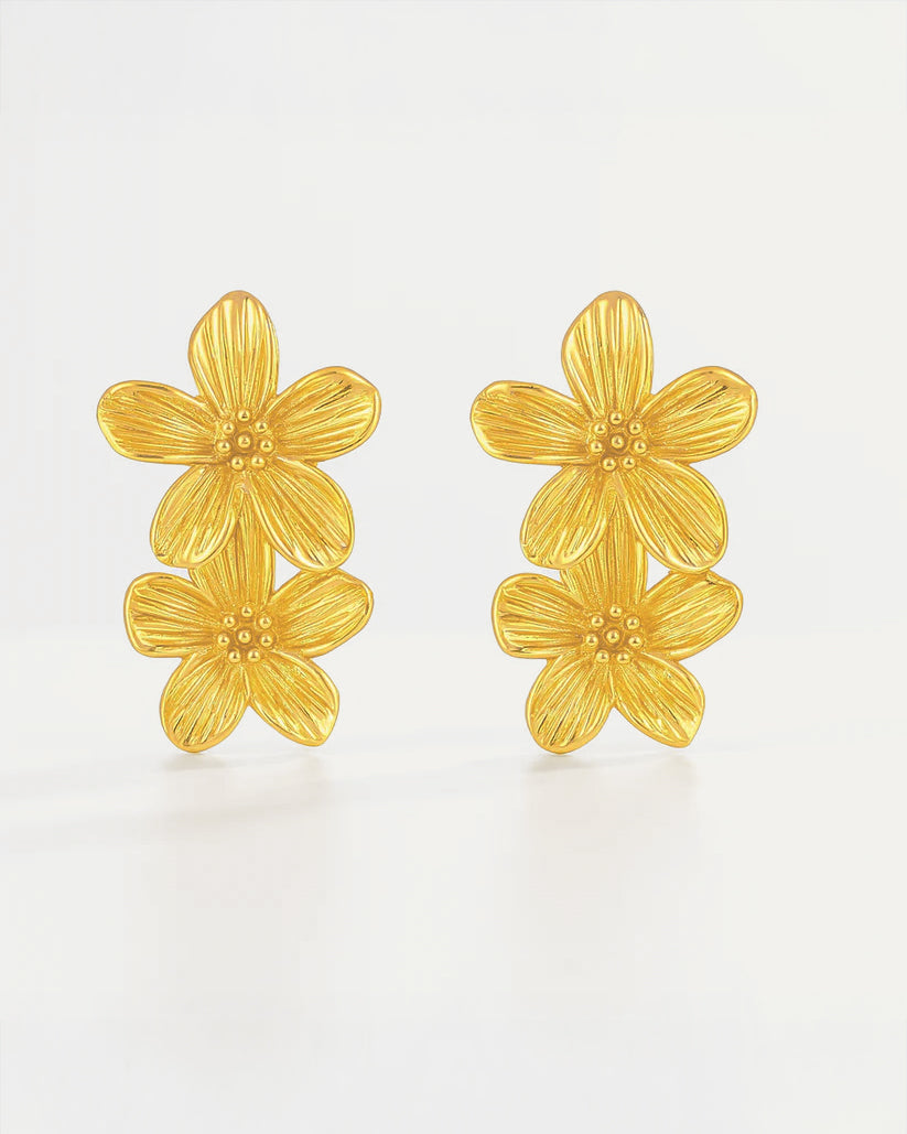 Pair of gold floral earrings on a light beige background