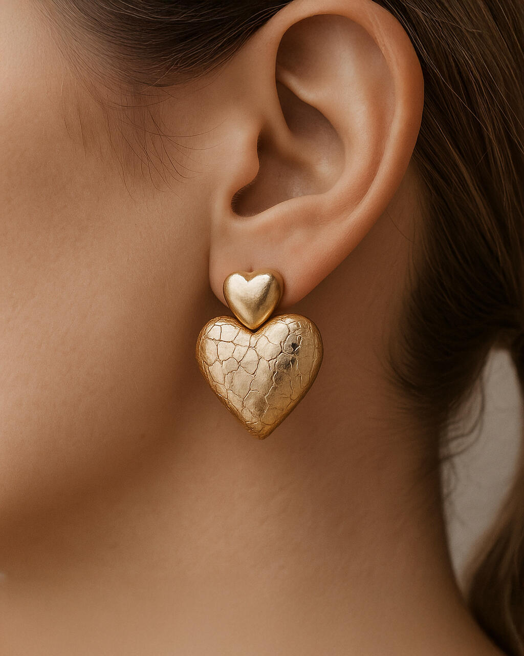 18K gold-plated hammered heart drop earrings close-up on model ear, elegant