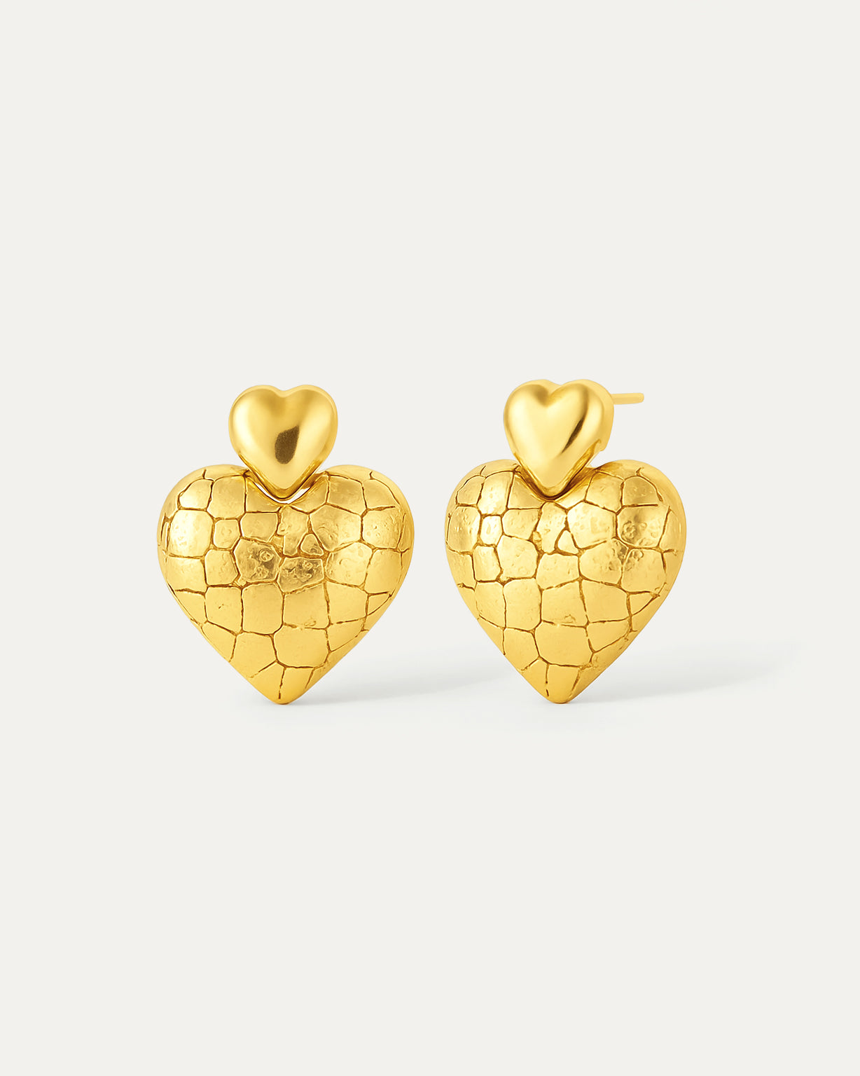 Gold heart-shaped earrings on a light gray background