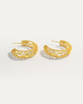 18K gold-plated openwork hoop earrings with geometric filigree design on studio background