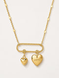 Gold necklace with heart-shaped pendants on a light gray background