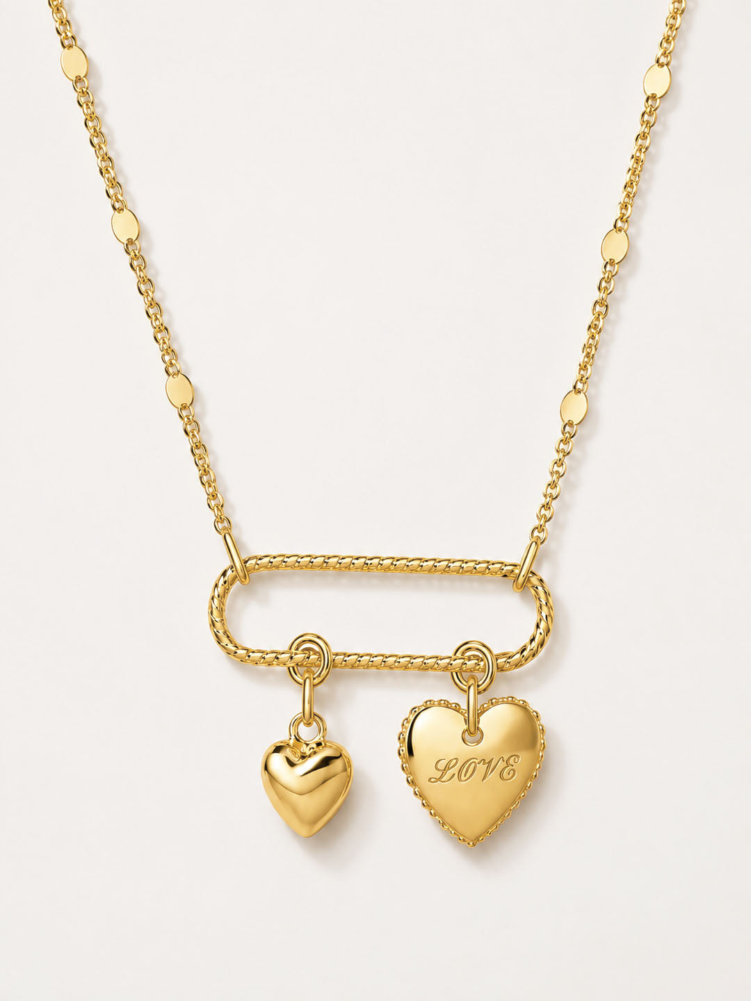 Gold necklace with heart-shaped pendants on a light gray background