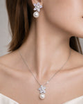 Pearl drop flower earrings and matching necklace in gold plated finish, worn on model