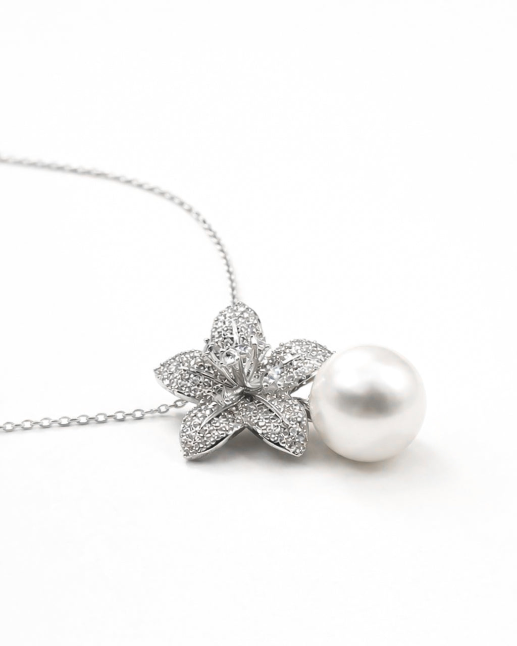 Pearl drop flower pendant necklace with zircon stones, gold plated side flat lay