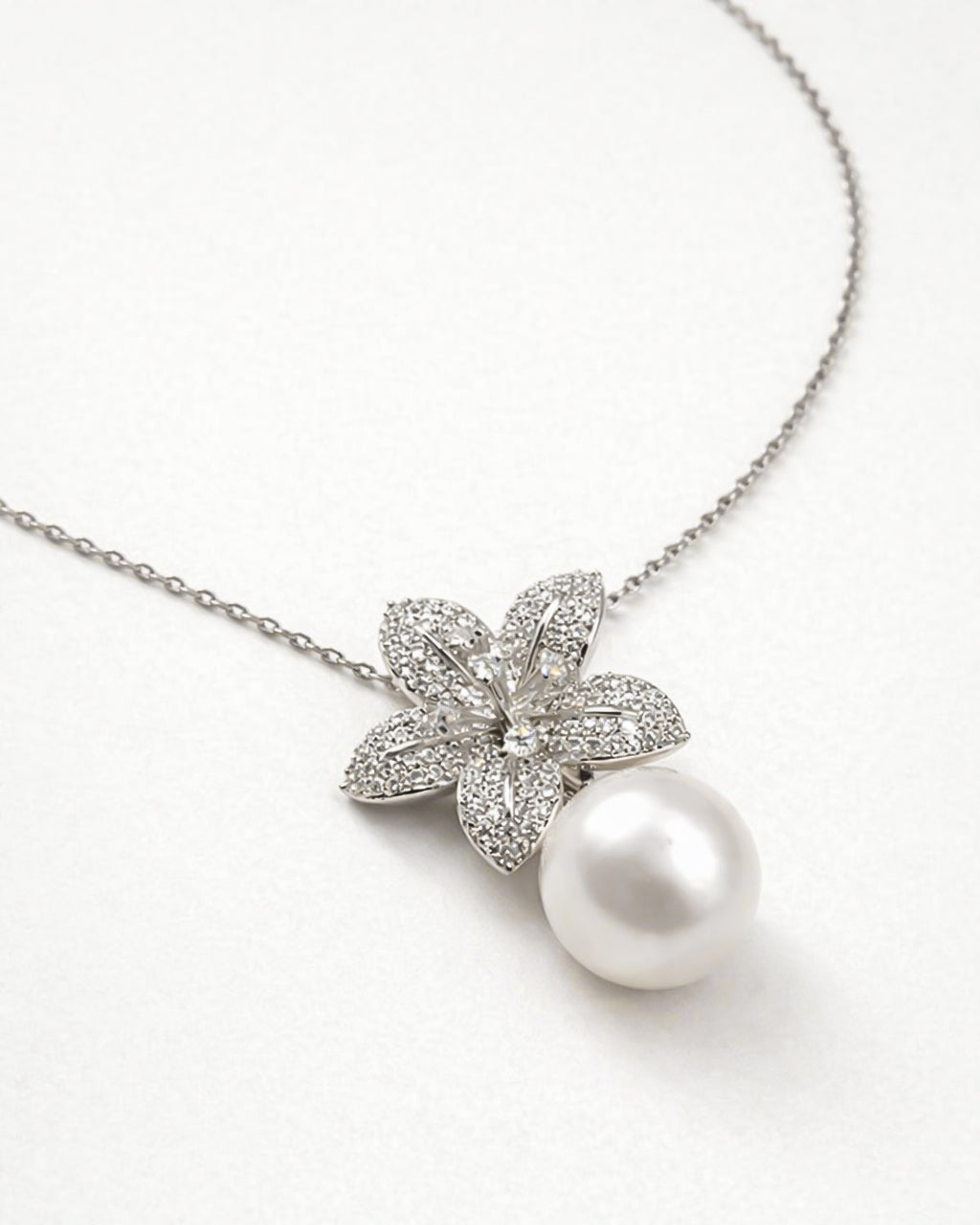 Pearl drop flower pendant necklace with zircon stones, gold plated finish flat lay