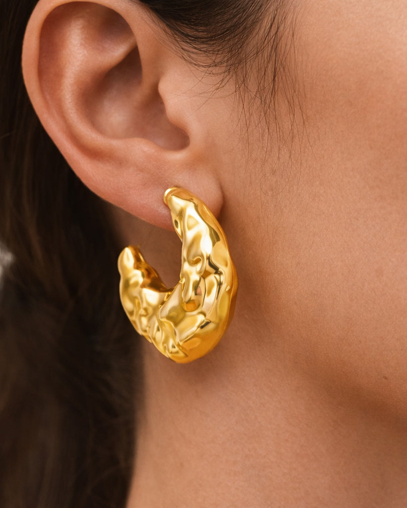 Close-up model wearing molten sculpt hoop earrings in 18k gold-plated brass