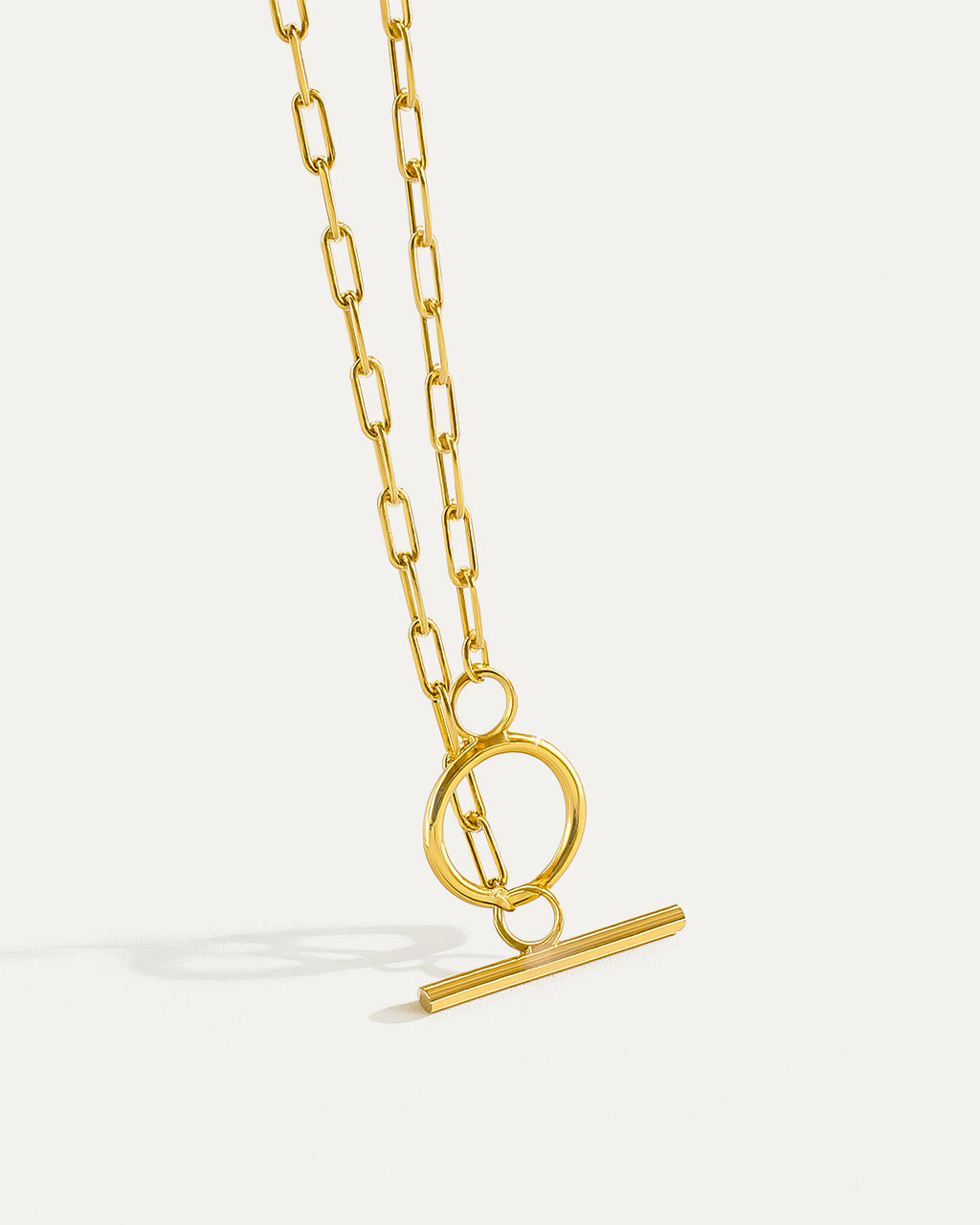 Gold necklace with a unique clasp design on a light gray background