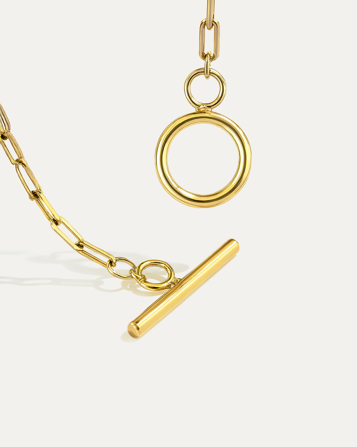 Gold necklace with circular and bar pendants on a white background