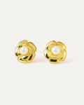 A close-up studio shot of a pair of gold-tone flower stud earrings on a plain white or light beige background. Each earring f