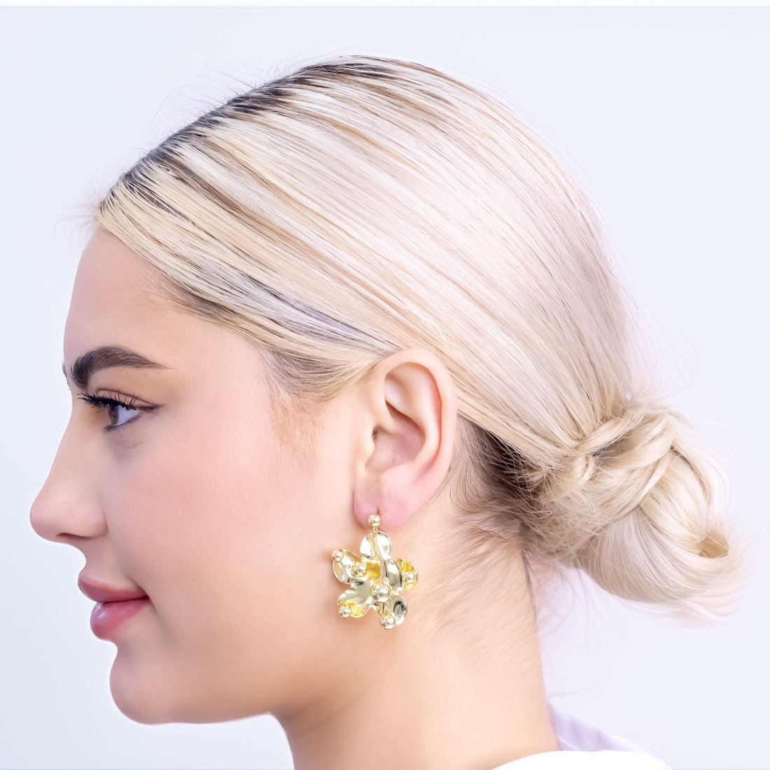 Gold-plated abstract flower-shaped drop earrings with smooth petals and decorative sphere accents on stud backing