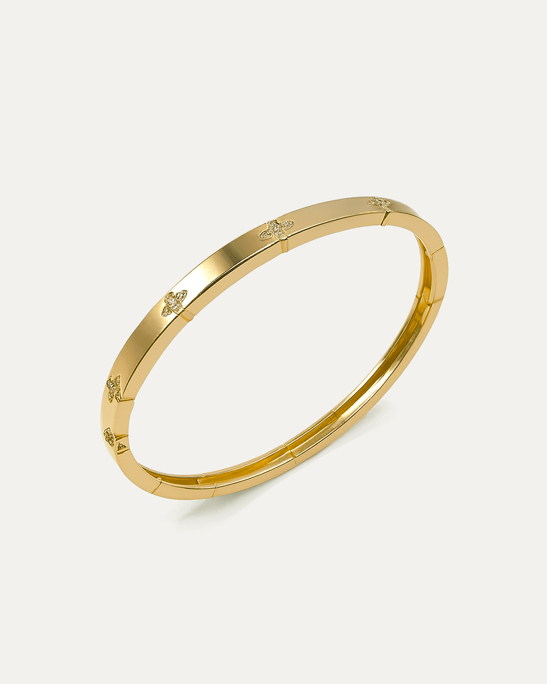 Angled view of a polished gold petite daisy bangle bracelet on a white background, showcasing the slim profile and multiple s