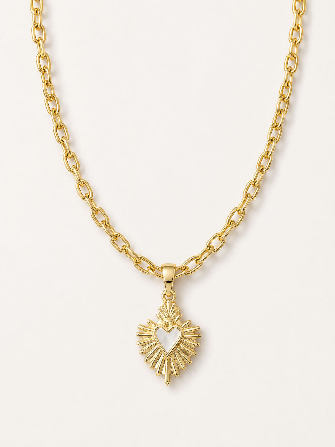 Gold necklace with a heart-shaped pendant on a light gray background