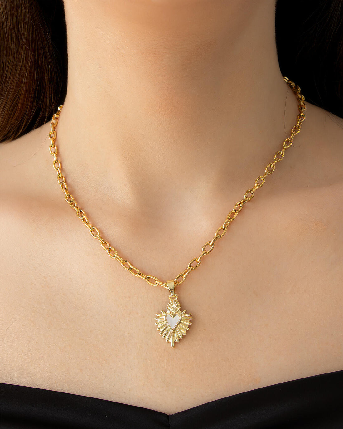 Gold jewelry set including necklace, earrings, and ring on a pink background with heart-shaped text.