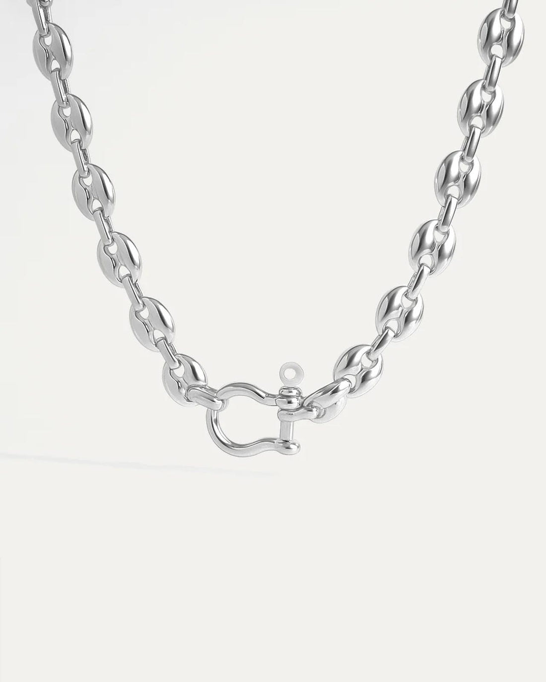 Model wearing chunky silver collar necklace with sculpted links and industrial-style shackle clasp.