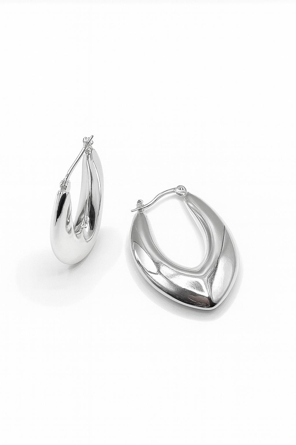 Close-up of sculpted silver hoop earrings in bold marquise teardrop shape with latch-back closure