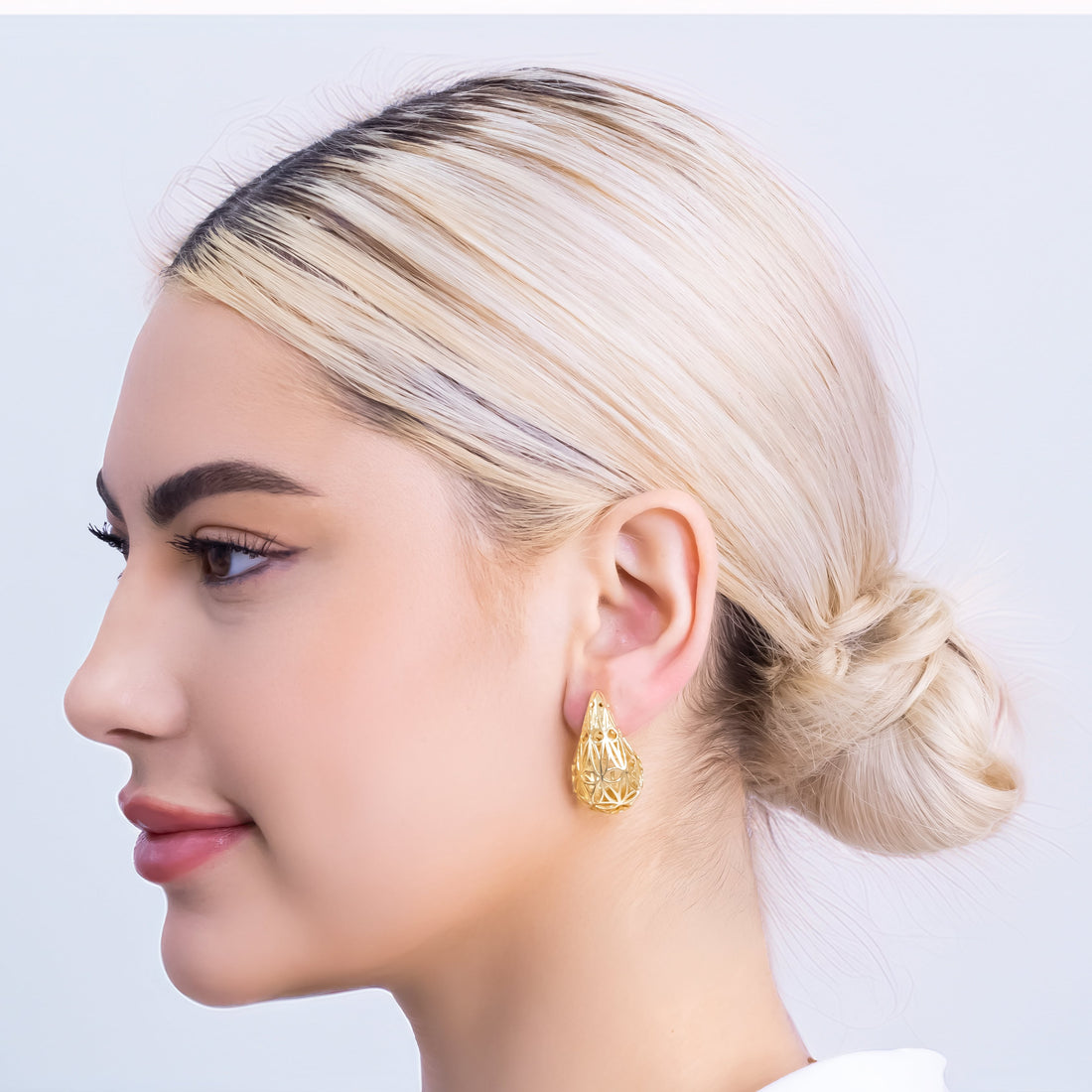 Gold-plated filigree earrings in spiral shell shape with intricate lace-like cutout pattern and stud backing