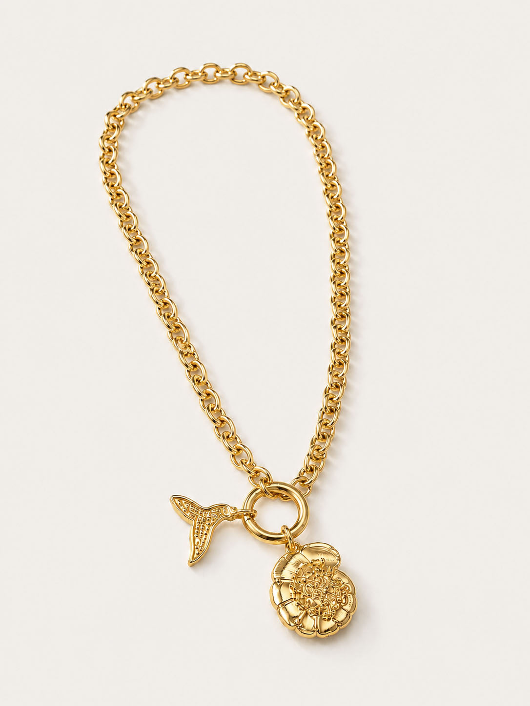 Gold chain necklace with a pendant on a light beige background