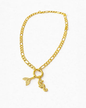Gold chain necklace with a mermaid tail and key pendant on a white background