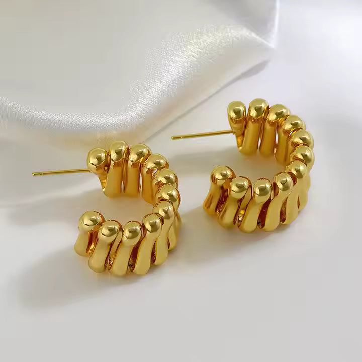 Gold-plated C-shaped earrings with stacked wave design featuring multiple curved ridges in a sculptural pattern