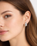 Silver teardrop flow drop earrings on model ear, modern minimalist jewelry style