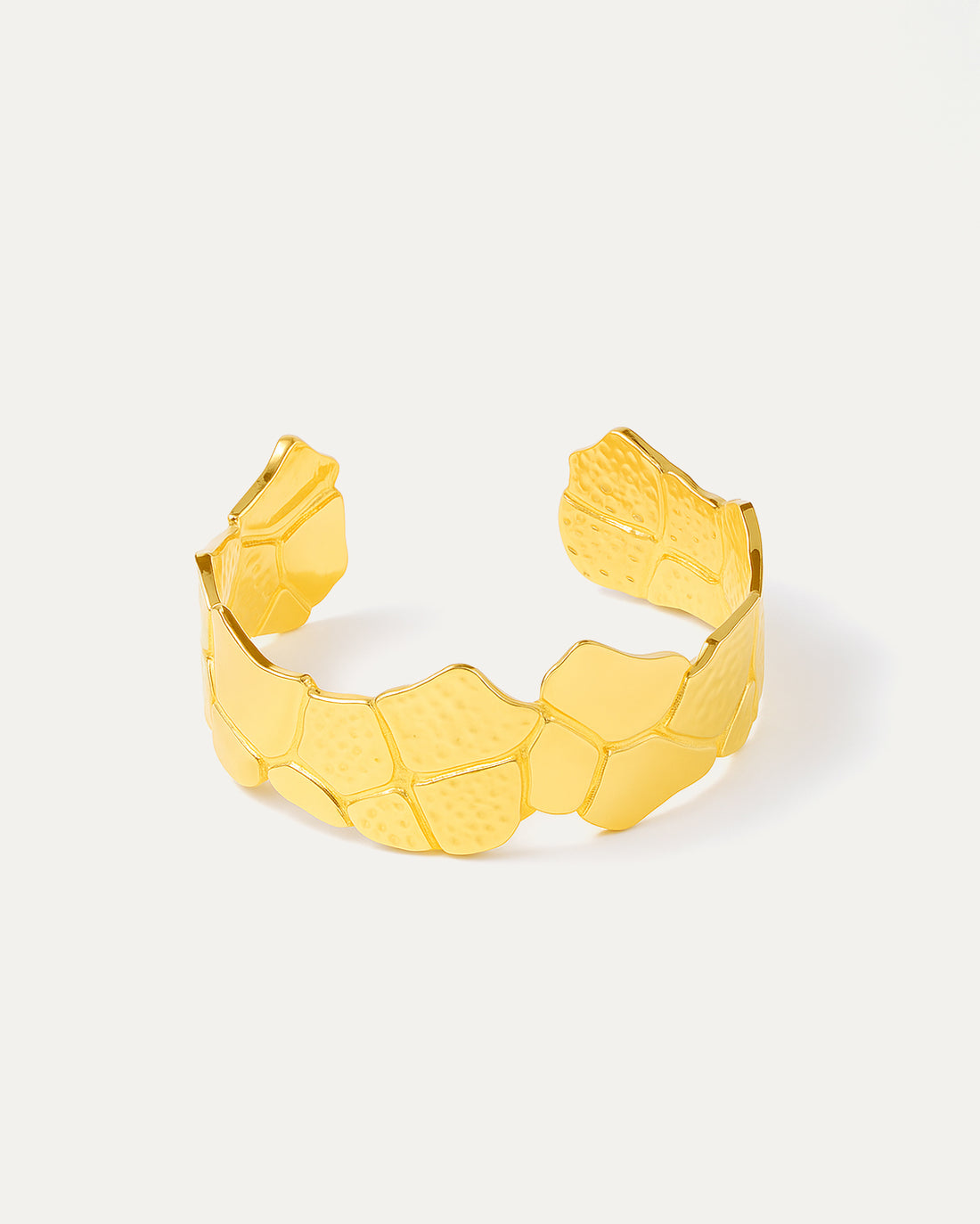 Gold bracelet with a textured pattern on a white background