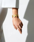 Hand wearing gold bracelets and rings on a white background