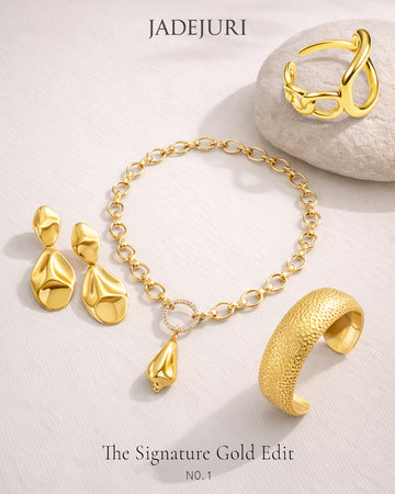 Gold jewelry set including earrings, bracelet, and ring on a light background with 'JADEJURI' branding.