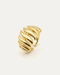 Gold ring with wavy design on a light beige background
