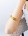 Gold bracelet on a person's wrist against a light background