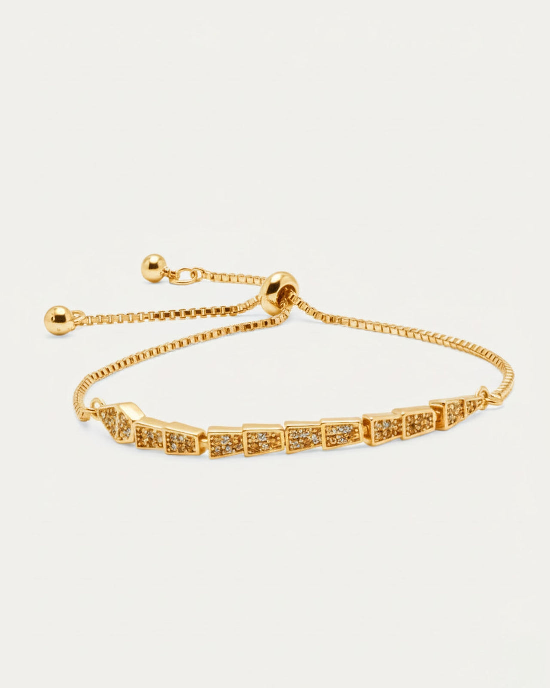 A gold-plated slider bracelet with a delicate chain and a serpentine, geometric centerpiece. The adjustable bracelet features
