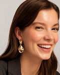 Model wearing abstract gold-plated dangle earrings, minimalist statement style