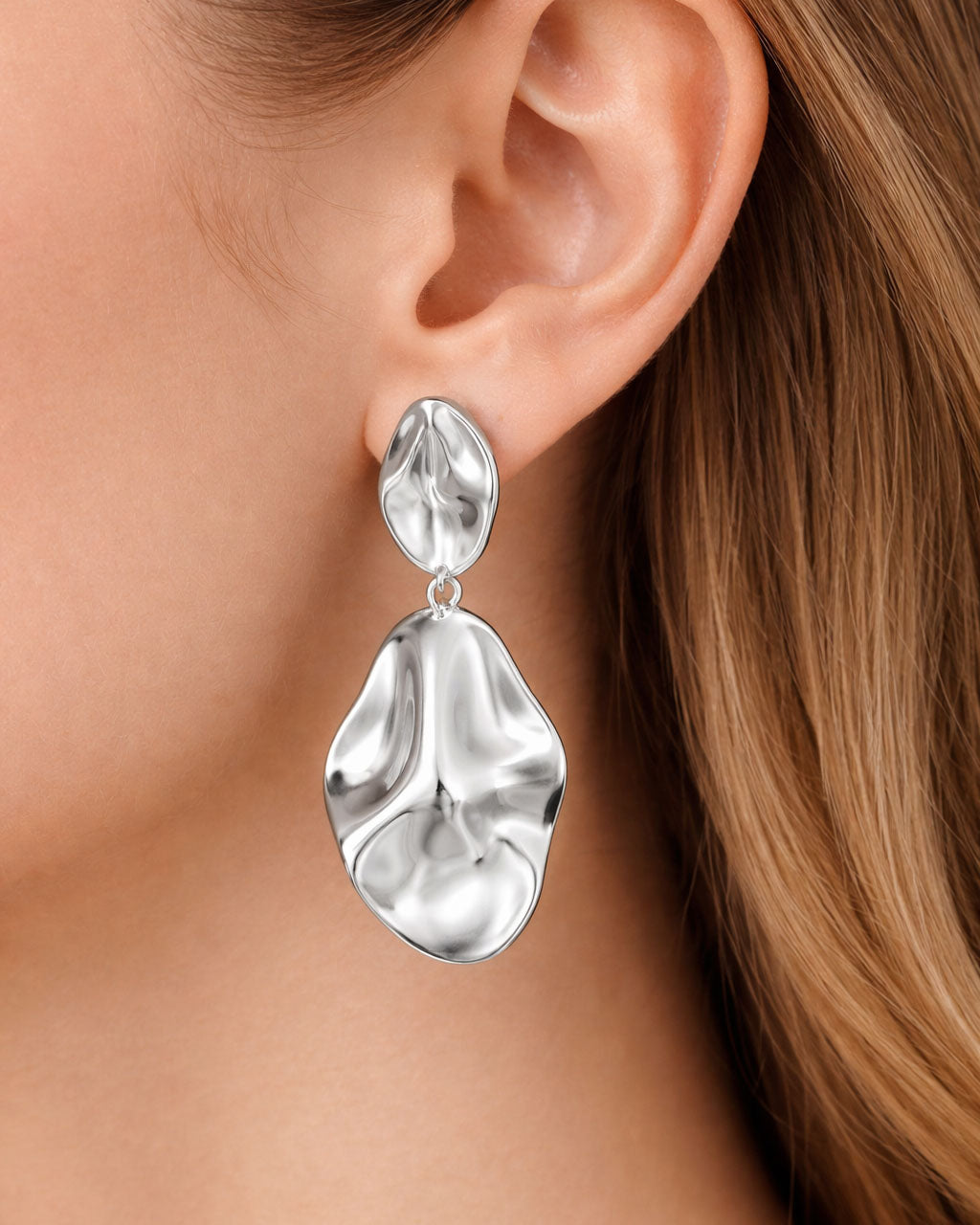 Model wearing abstract silver dangle earrings with sculptural organic design