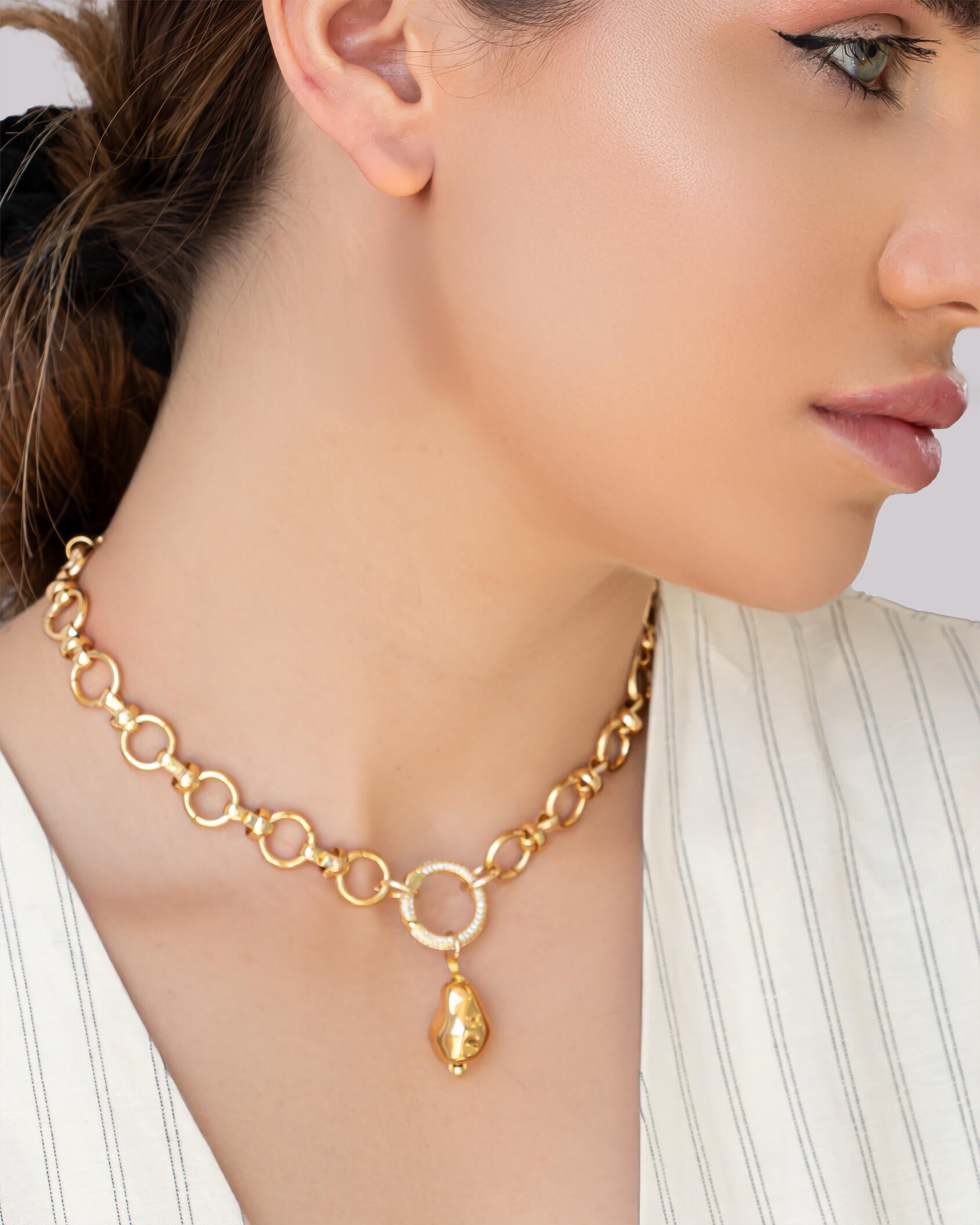 18K gold-plated brass necklace with circular link chain, pavé crystal ring, and pebble charm pendant on model