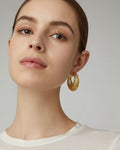 18K gold-plated baroque crescent hoop earrings worn on model with intricate sculpted texture